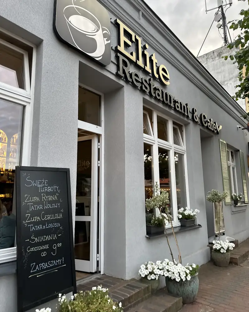 Szara fasada Elite Cafe & Restaurant z tablicą menu przed wejściem